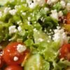 Vibrant salad with fresh greens, colorful vegetables, and a creamy dressing.