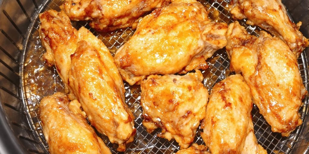 Crispy golden chicken wings in an air fryer basket.