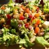 Jamie Oliver salad with fresh ingredients on a wooden board.