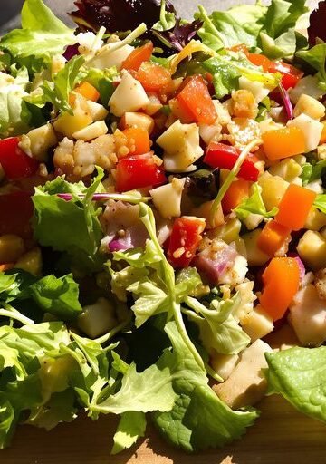 Jamie Oliver salad with fresh ingredients on a wooden board.