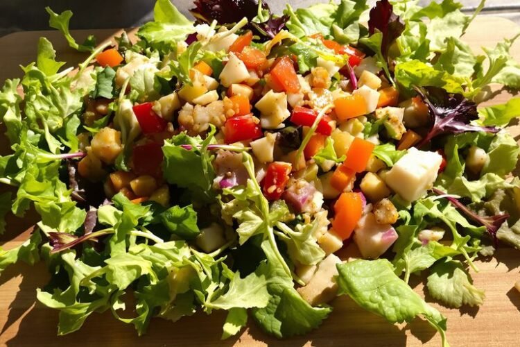 Jamie Oliver salad with fresh ingredients on a wooden board.