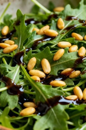 Rocket salad with balsamic glaze and pine nuts.