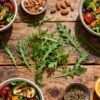 Colorful salads with fresh rocket leaves on wooden table