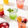 Colorful non-alcoholic party drinks with fruit garnishes.
