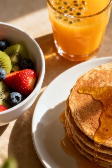 Healthy breakfast spread with fruit, pancakes, and juice.