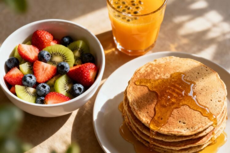 Healthy breakfast spread with fruit, pancakes, and juice.