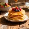 Stack of pancakes with berries and honey for breakfast.