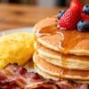 Delicious breakfast spread with pancakes, bacon, and omelet.