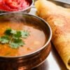 South Indian food spread with dosa, sambar, and chutney.
