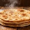 Stack of freshly cooked, golden-brown roti flatbreads.