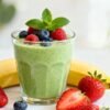 Healthy green breakfast shake with fresh berries and fruit.