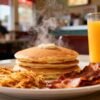 Affordable breakfast plate with pancakes, bacon, and hash browns.