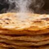 Stack of fluffy, golden-brown rotis with steam rising.