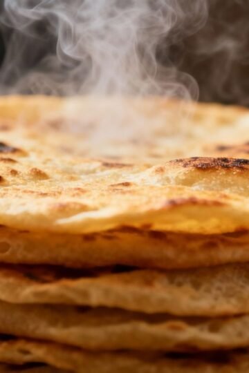 Stack of fluffy, golden-brown rotis with steam rising.