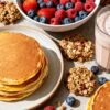 Muscle-building breakfast spread with pancakes, berries, and protein shake.