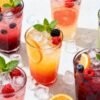 Assorted colorful mocktails with fresh fruit garnishes.