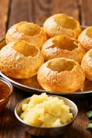 Crispy pani puris with bowls of flavored water.